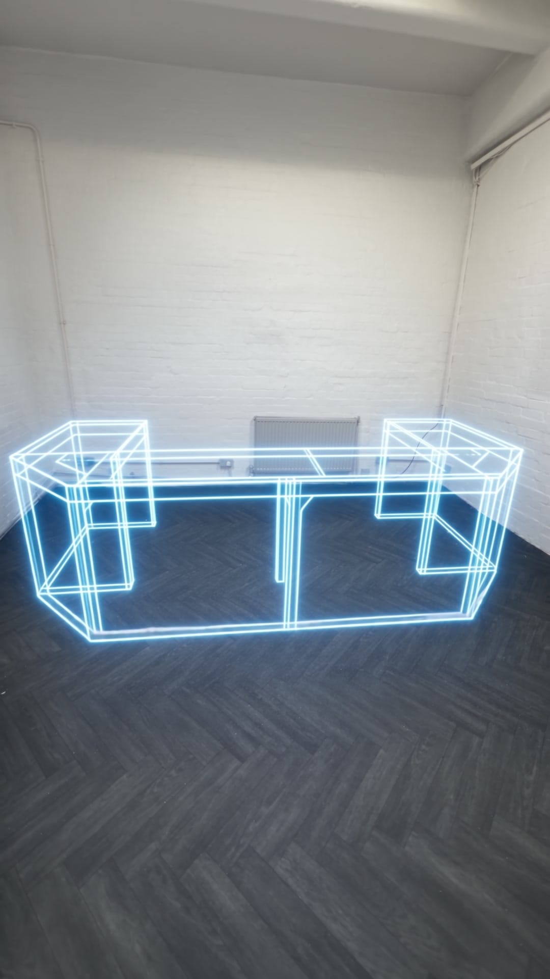 The DJ booth drawn as a blue wireframe outline standing in the empty room, before it was built