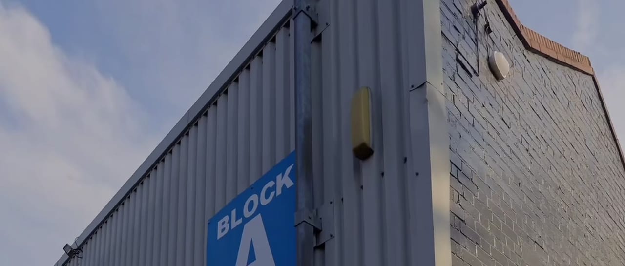 The approach to Scope Media Studios: the grey profiled-steel industrial unit with the blue BLOCK A sign on its flank.