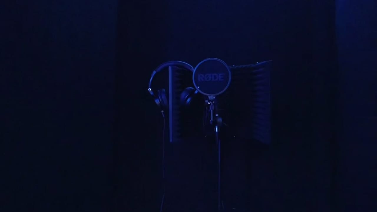 The recording studio lit by violet LED strips, with the desk, monitors and acoustic panelling