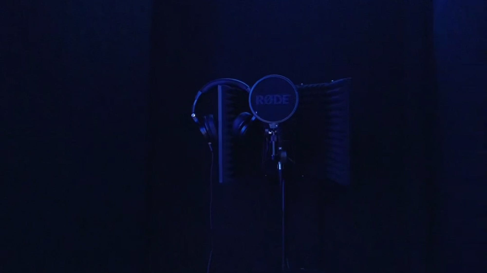 The recording studio lit by violet LED strips, with the desk, monitors and acoustic panelling