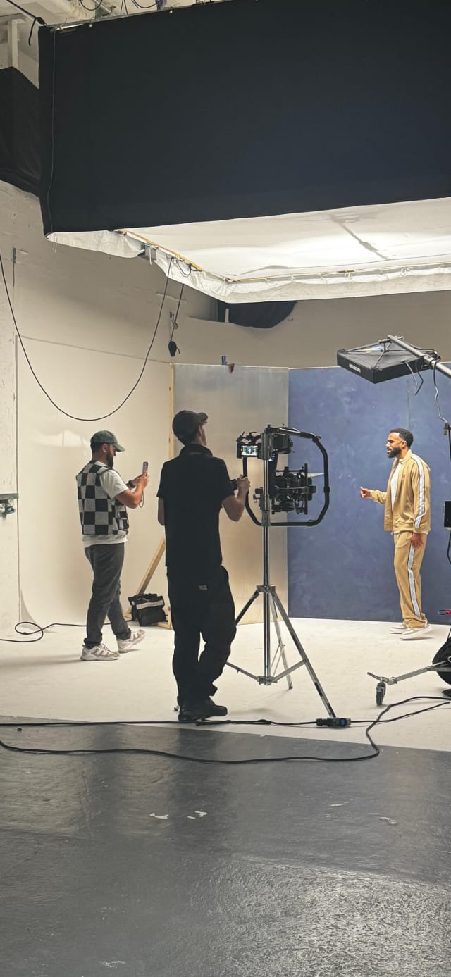 A gimbal operator filming a subject against a painted blue flat in Studio A