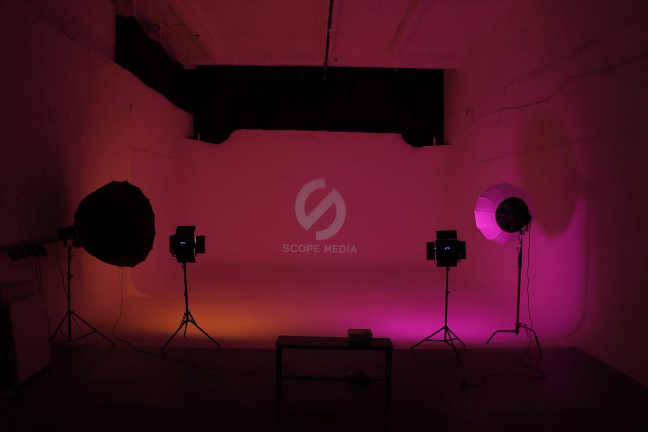 Studio A's infinity cove washed in a magenta-to-orange gradient with the Scope Media Studios logo projected across it