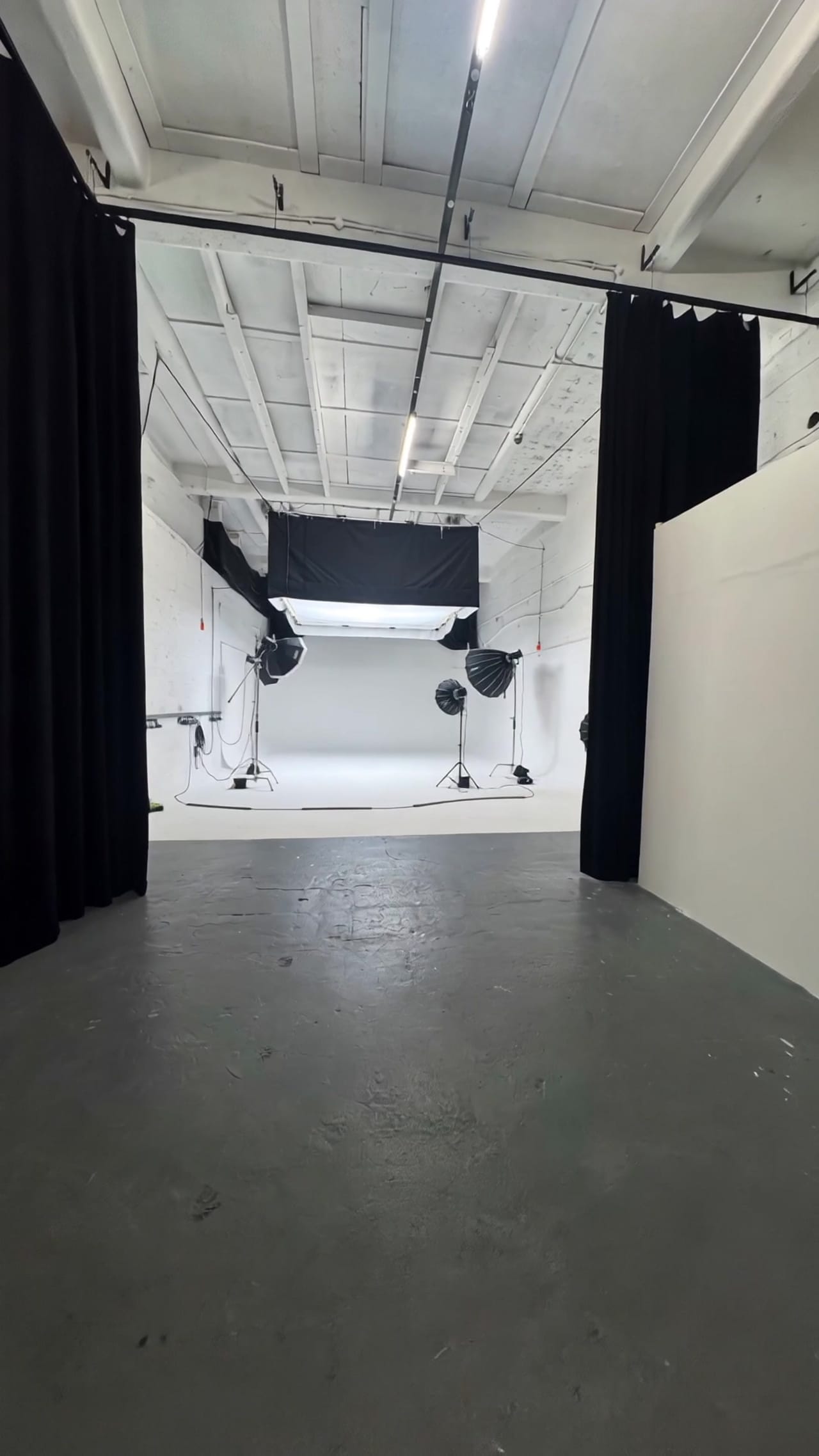 Studio A rigged for a shoot with softboxes on stands and an overhead silk above the white infinity cove