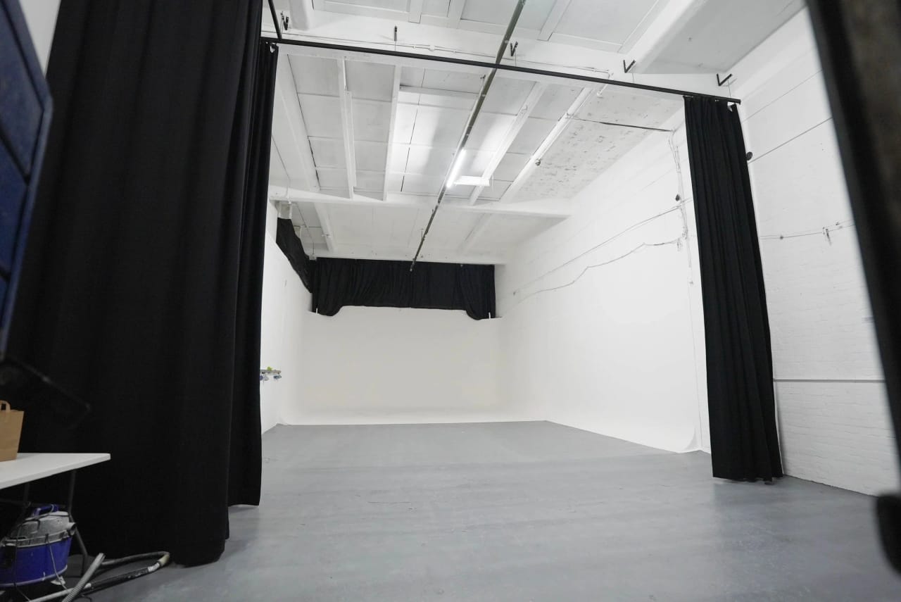 Wide view of Studio A showing the full length of the white cove, the grey floor and the curtain track