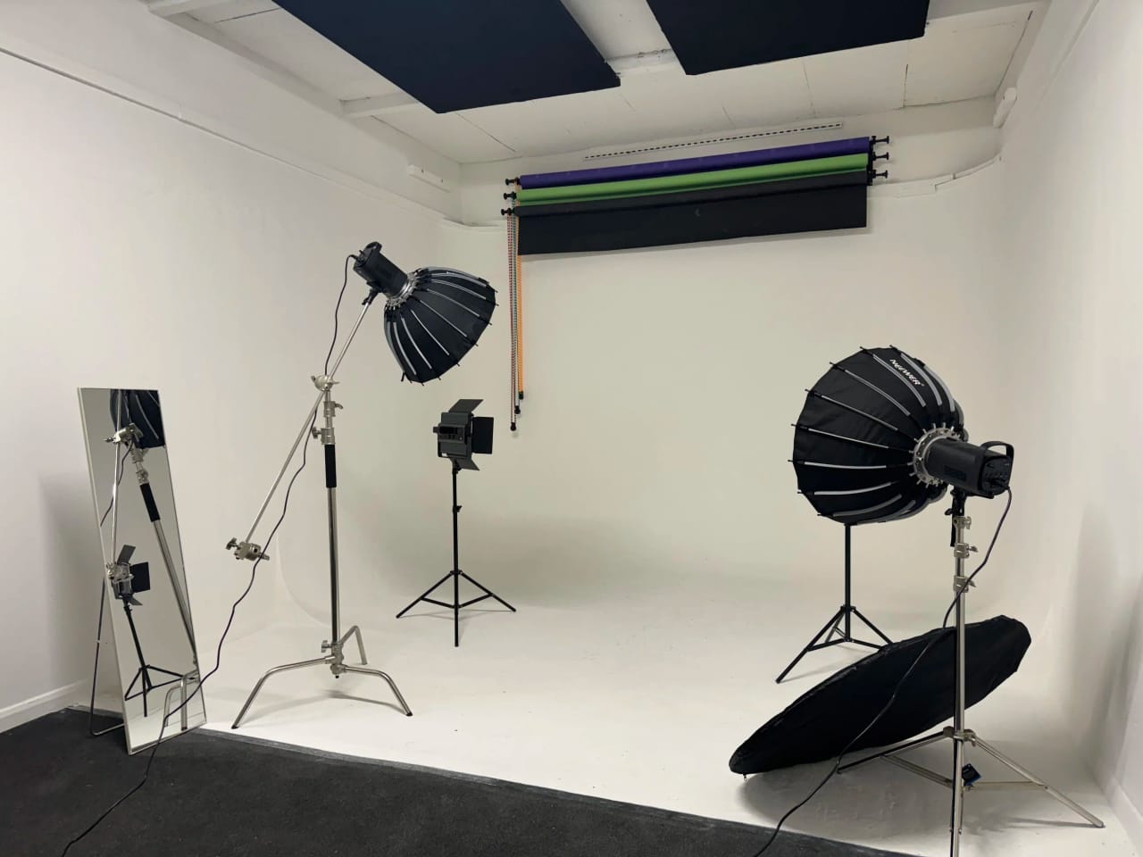 Studio B under neutral white light showing the curved cove and the wall-mounted backdrop roll bar