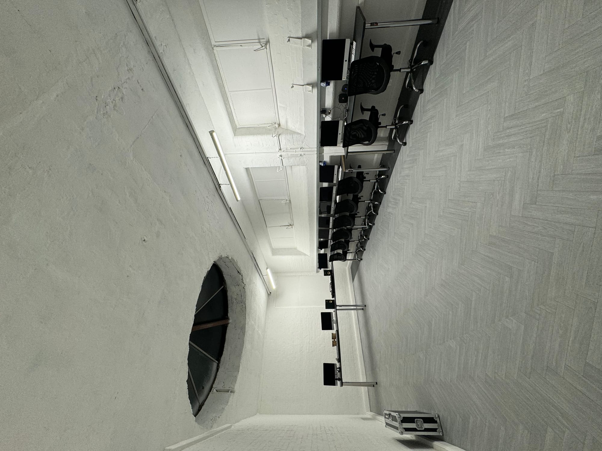 The workshop room: two benches of iMac workstations with black office chairs beneath an original circular ceiling light well