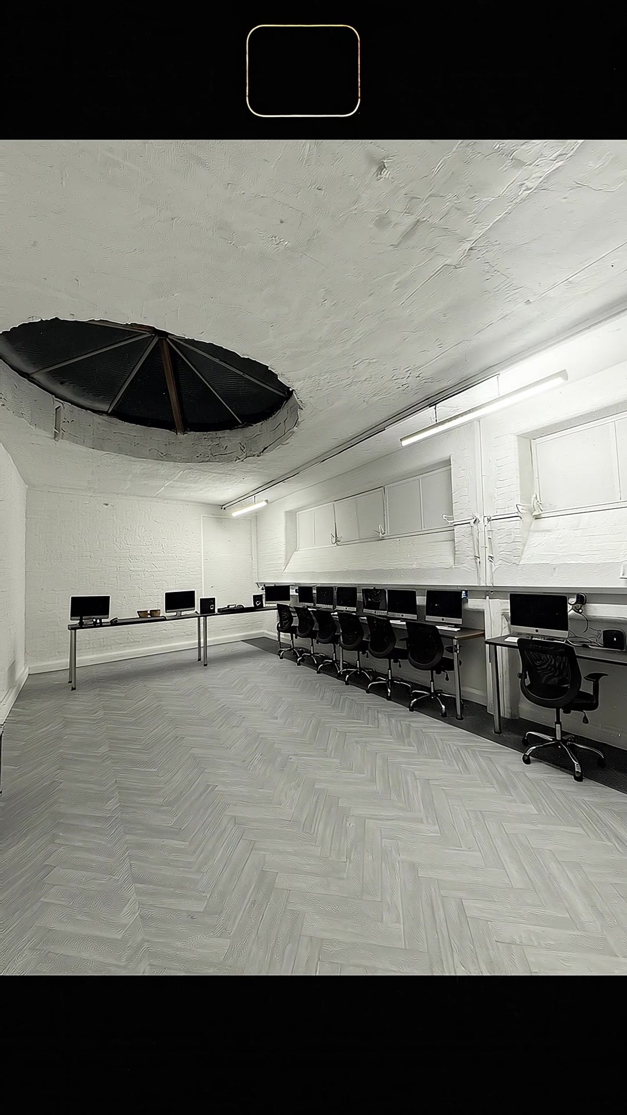 The workshop workstations and herringbone floor, with the circular ceiling light well overhead.
